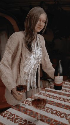 a woman standing at a table with two wine glasses in front of her and a bottle of wine to the side