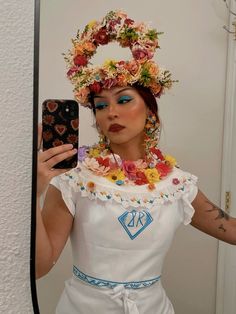 a woman with flowers on her head taking a selfie