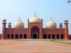 a large red building with two domes on it's sides and people standing in front