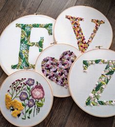 embroidered letters and numbers are arranged on the table with flowers in each letter, which spell out the word love