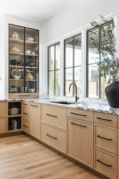 a kitchen with wooden cabinets and white counter tops, an open window to the outside