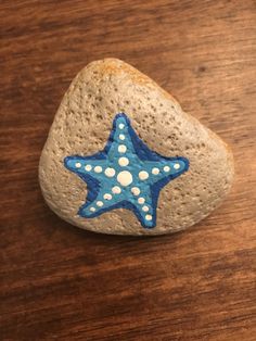 a rock with a starfish painted on it sitting on top of a wooden table