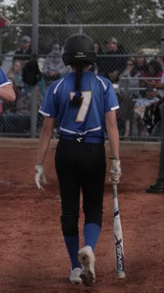 a softball player walking to the dugout with her bat in hand and people watching