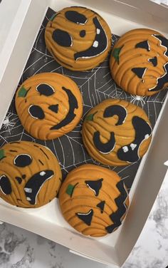 four decorated halloween cookies in a white box