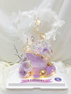 there is a purple cake with white flowers on top and a tiara atop it