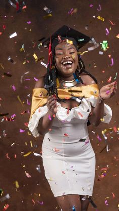 a woman wearing a graduation cap and gown surrounded by confetti