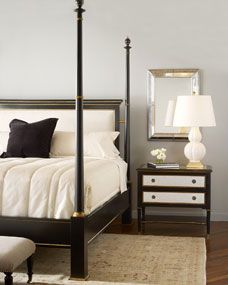 a bedroom with a four post bed, night stand and mirror on the wall above it