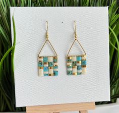 a pair of earrings sitting on top of a wooden stand next to a potted plant