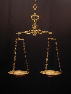 a golden scale with two balances on each side and a black background behind it