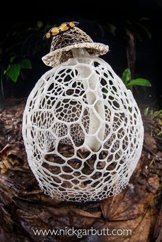 an intricately designed object sitting on top of leaves in the middle of the forest