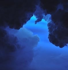 the sky is dark and blue with clouds in it, as seen through an opening