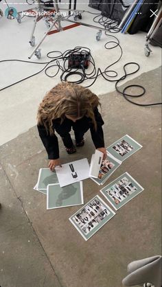 a person kneeling down on the ground in front of some pictures with their hands over them