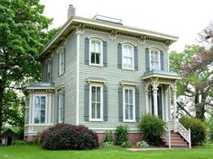 a gray house sitting on top of a lush green field