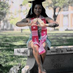 a woman sitting on top of a cement bench wearing a graduation cap and holding her hands together