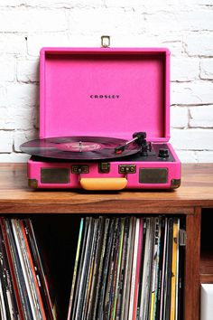 a pink record player sitting on top of a wooden table