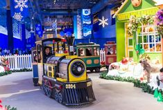 a small train is on display in a toy store decorated with snowflakes and christmas decorations