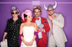 a group of people standing next to each other in front of a purple wall wearing costumes