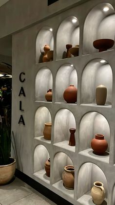 several vases are displayed on shelves in front of a wall that says caja