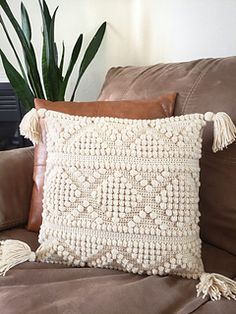 a brown couch with two pillows and a potted plant