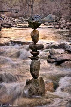 rocks stacked on top of each other in the middle of a river with water rushing behind them