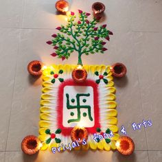 a decorated diya with candles and a tree on the floor in front of it