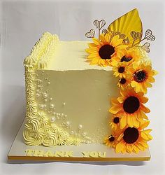 a white cake with yellow frosting and sunflowers