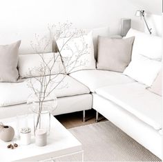 a living room with white couches and pillows