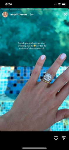 a woman's hand with a diamond ring on top of her finger, next to a pool