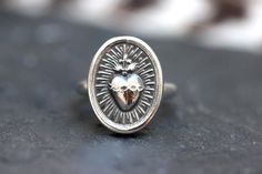 This listing is for one beautifully detailed sterling silver Sacred Heart medal ring. The Sacred Heart of Jesus ring features intricate details and is forged from pure sterling silver using steel dies.  These dies were made from vintage Catholic medals and this piece is unique with its vintage look. It is dimensional and sturdy. The band is thick 9 gauge half round sterling silver and the sterling silver coin focal is thick and sturdy. Wear this powerful symbol to show your faith and love.  - Choose your size at checkout!  - Sacred Heart measures 19mm by 15mm.  -Ring band measures 2.5 wide. - Made to Order: each piece will vary slightly in the overall shape of the coin, but yours will be just as beautiful and detailed!  - All items come gift wrapped, ready to give away or to treat yourself Heart-shaped Engraved Sterling Silver Ring, Silver Heirloom Heart Ring Gift, Silver Heirloom Heart Ring, Silver Heirloom Hallmarked Heart Ring, Jesus Ring, Milagro Heart, Burning Heart, Sacred Heart Of Jesus, Catholic Medals