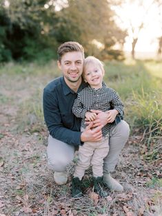 a man holding a little boy in his arms while he is smiling at the camera