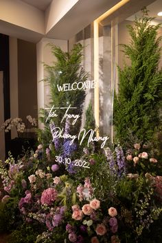 a welcome sign surrounded by flowers and greenery