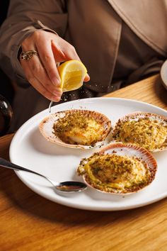 a person is sprinkling lemon onto some food on a white plate with silverware