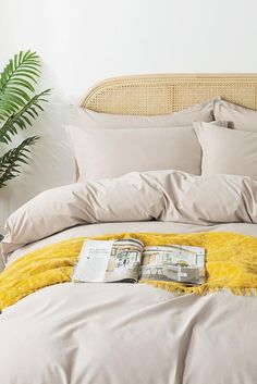 a bed with yellow blankets and pillows on top of it next to a potted plant