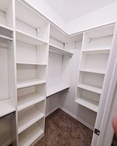 an empty walk - in closet with white shelving and carpeted flooring is shown