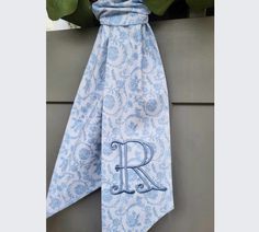 a blue and white tie with the letter r on it hanging from a window sill