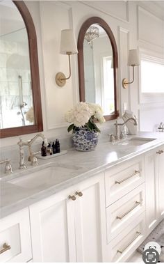 a white bathroom with double sinks and mirrors