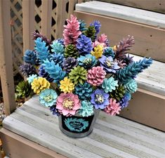 a vase filled with colorful flowers sitting on top of a wooden bench