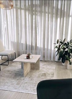 a living room filled with furniture and a large window covered in sheer draping