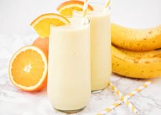 two glasses filled with orange smoothie next to bananas