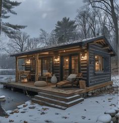 a small cabin sits in the snow next to a dock with chairs and tables on it