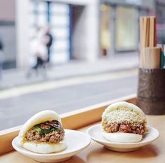 two small plates with food on them sitting on a window sill next to a building