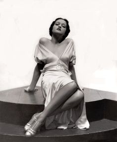 a woman sitting on top of a set of stairs wearing high heels and a dress