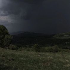 a dark sky with storm clouds over the mountains