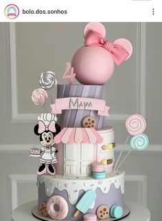 a cake with minnie mouse on top and other items around it that are pink, blue, white, and grey