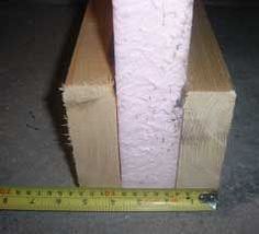 a roll of toilet paper sitting on top of a wooden block next to a ruler