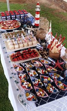 a table topped with lots of food on top of a grass covered field next to a red white and blue flag