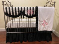 a black and white baby crib with pink monogrammed bedding