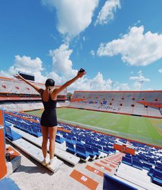 a woman in a black bathing suit standing on the bleachers at an empty stadium