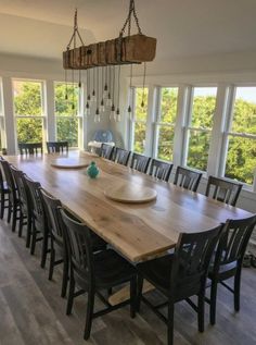 a large wooden dining table surrounded by black chairs and wood flooring with lots of windows