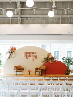 a room filled with white chairs next to a big sign